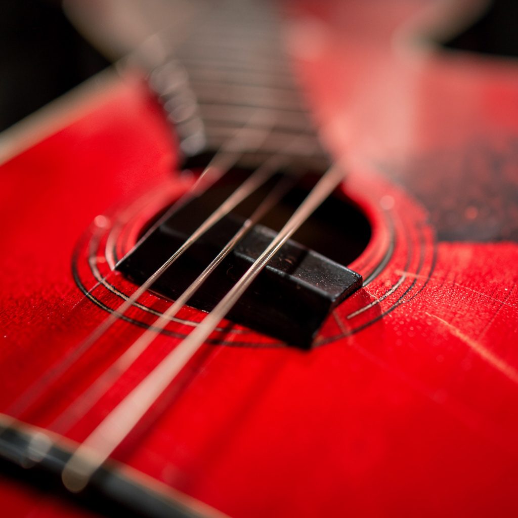 Close-up of warm honey-amber acoustic guitar finish and tightrope, evoking a touch of warmth in a calm, friendly atmosphere.