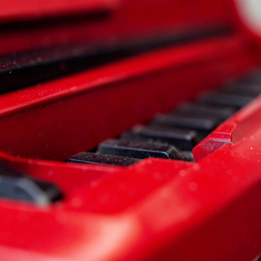 Close-up of a polished black digital piano keybed under warm stage lighting, with a soft amber and ivory glow across the keys.